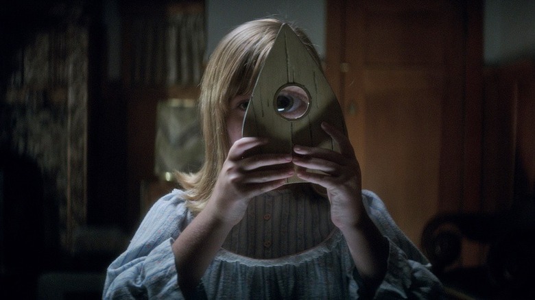 Doris holds a planchette to her eye