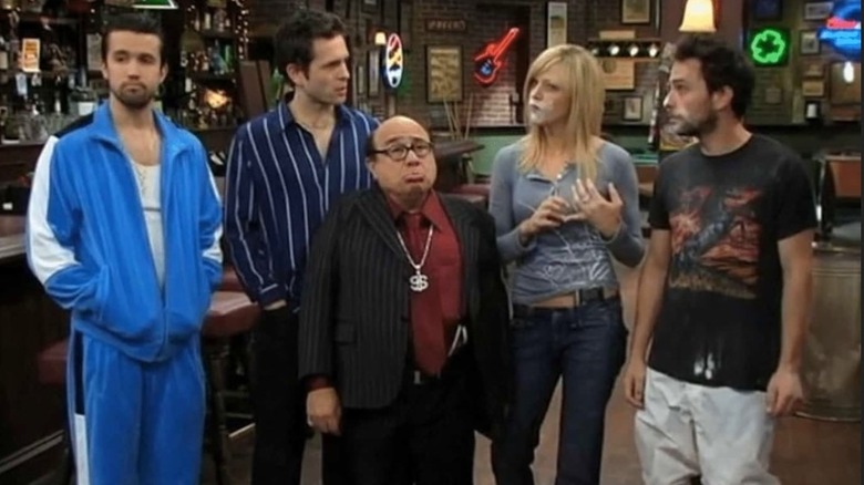 Mac, Dennis Reynolds, and Frank Reynolds dressed like wanna-be mobsters; Dee Reynolds and Charlie Kelly have white powder on their faces